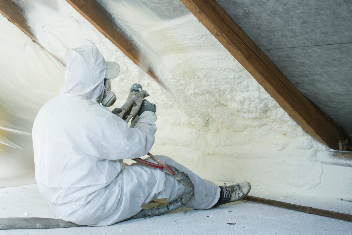 Technician spraying polyurethane spray foam insulation on a roofline
