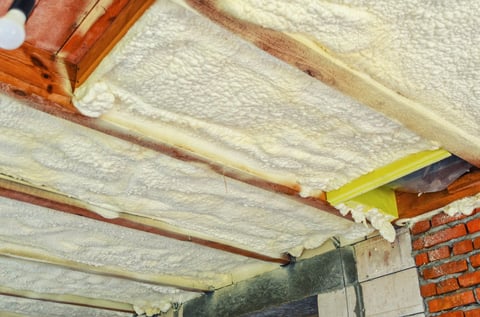 Spray foam insulation applied between ceiling beams inside a building