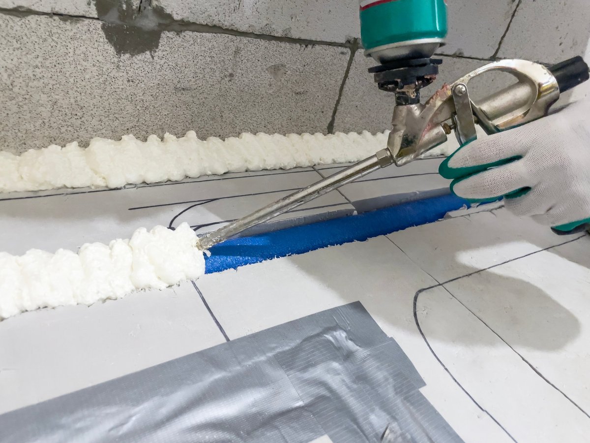 Worker applying insulation material with a spray gun during construction